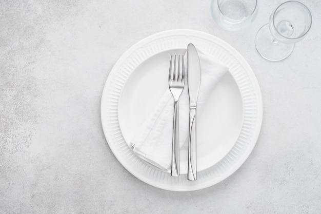 Cenário de mesa de restaurante com pratos, copos e talheres brancos