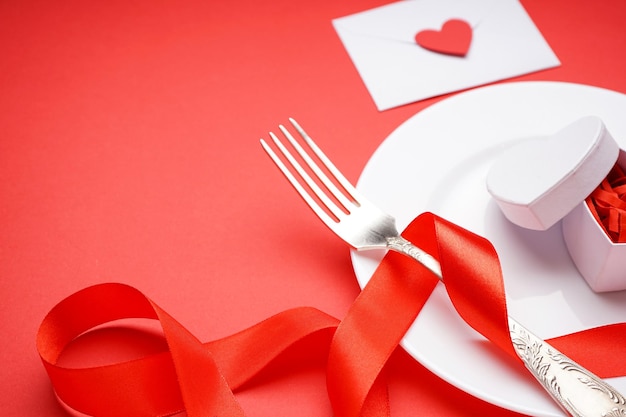 Cenário de mesa elegante e presente para o dia dos namorados em um fundo vermelho com espaço para texto, close-up.