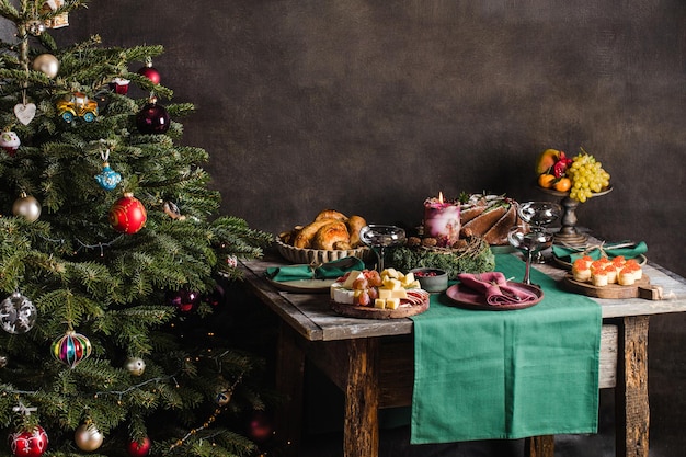 Cenário de mesa elegante para o jantar de natal em família com a árvore de natal no fundo e presentes na ...