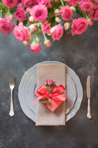 Cenário de mesa romântica com rosas, louça vintage, talheres.