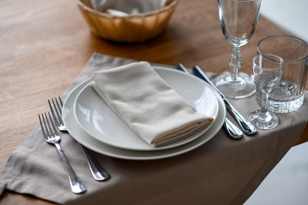 Cenário de mesa romântico festivo com guardanapo cinza talheres e louça branca na toalha de mesa de seda bege