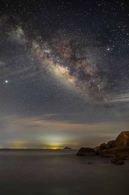 Cenário de tirar o fôlego da via láctea no céu noturno panorâmico sobre a paisagem marítima