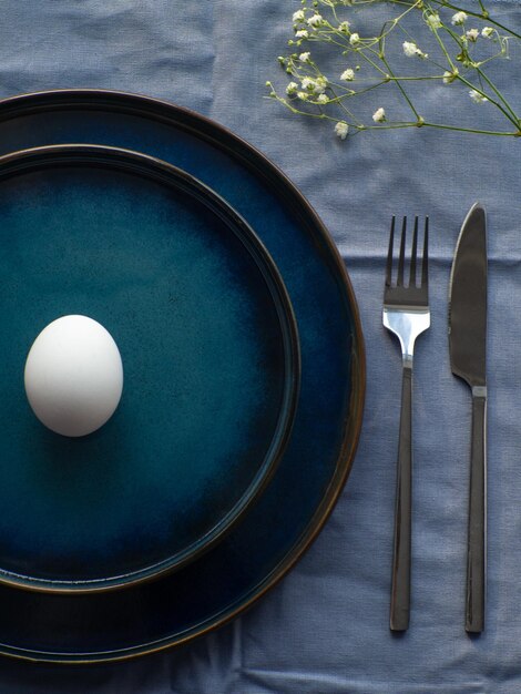 Cenário festivo de mesa de Páscoa com ovo e flores sobre fundo azul