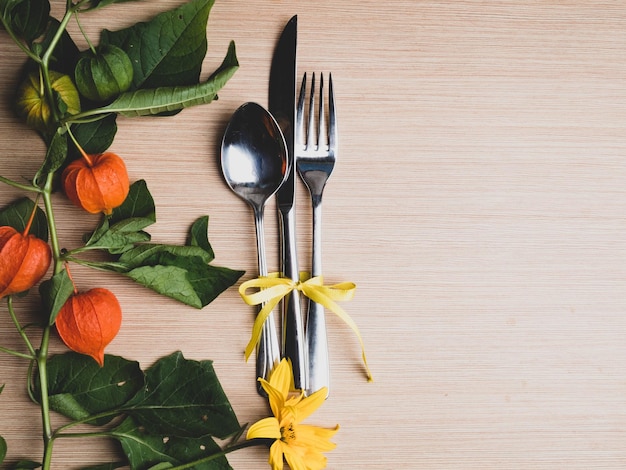 Cenário temático de outono com uma colher de faca e garfo decorado com ramo de physalis de flor amarela