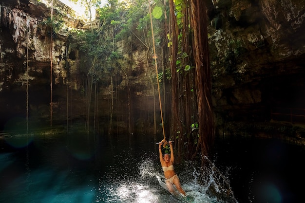 Cenote Ik-Kil Yucatan. Garota em um bungee. México.