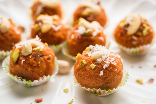 Cenoura halwa laddu ou bolinhos doces, servidos em um prato com coberturas de frutas secas. foco seletivo