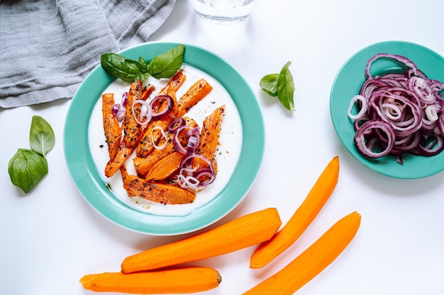 cenouras fritas com cebola roxa e creme de iogurte feta. Almoço vegetariano de cenouras e cebolas douradas,