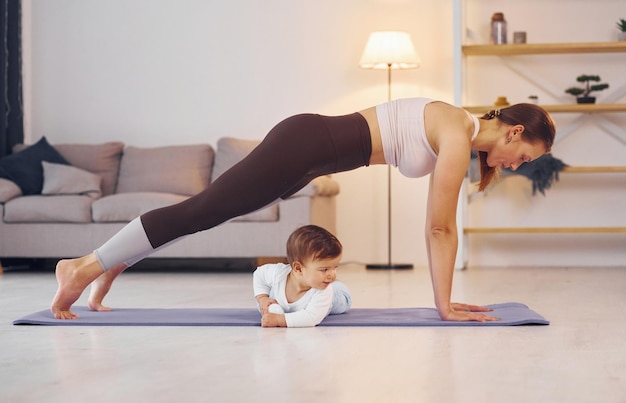 Centrado en ejercicios de yoga Madre con su pequeña hija está en casa juntos