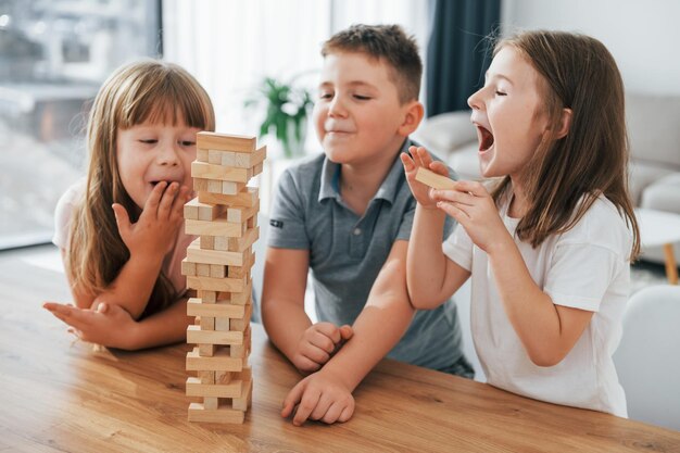 Foto centrado en el juego de la torre jumbling los niños se divierten juntos en la sala doméstica durante el día