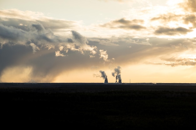 Una central térmica con mucho humo saliendo de las tuberías con un cielo oscuro y dramático sobre ella Concepto de energía alternativa de contaminación del aire y conceptos de producción de gas natural