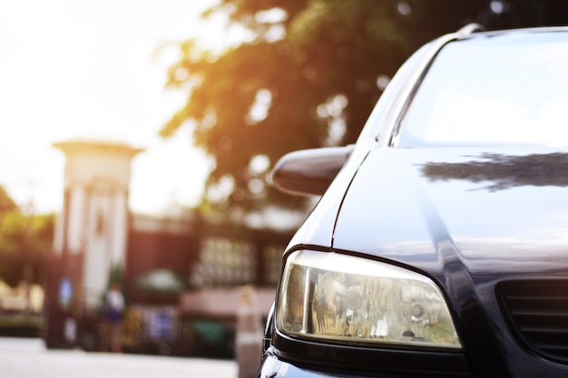 Centrándose en los faros negros del coche en una esquina con luz solar, faros de primer plano