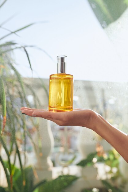 Centrarse en la botella de perfume en la mano de la mujer.