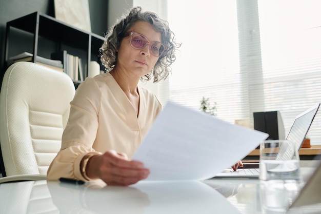 Centrarse en la directora ejecutiva madura leyendo un documento financiero