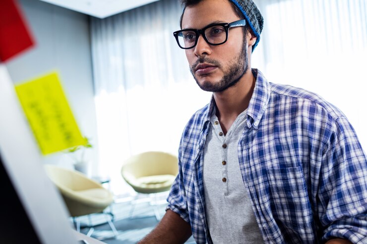 Foto centrarse en el hombre inconformista que trabaja en el escritorio de la computadora