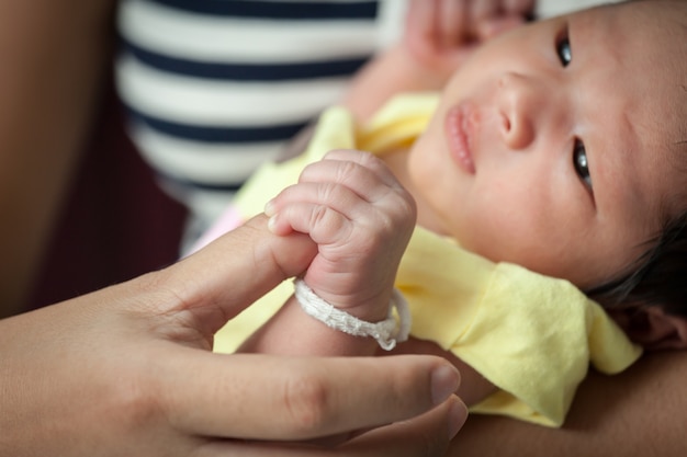 Foto centrarse en la mano del bebé recién nacido mientras está acostado en la mano de la madre
