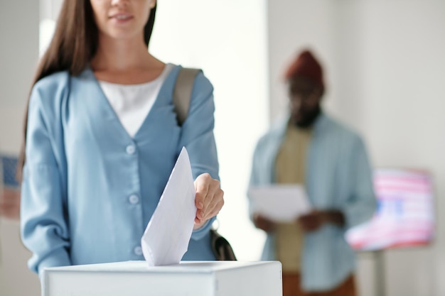 Foto centrarse en la mano de una joven votante poniendo papeleta en la caja