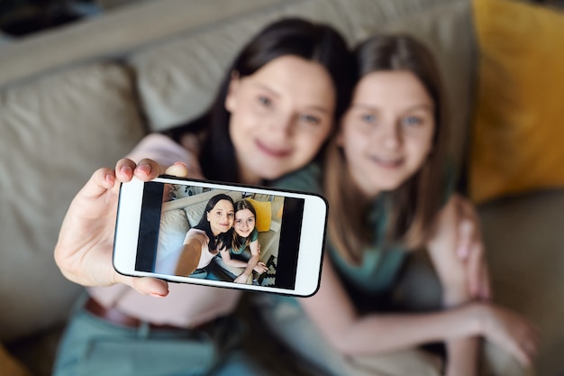 Foto centrarse en la pantalla del teléfono inteligente con selfie de madre e hija, estrecha relación entre el concepto de madre e hija