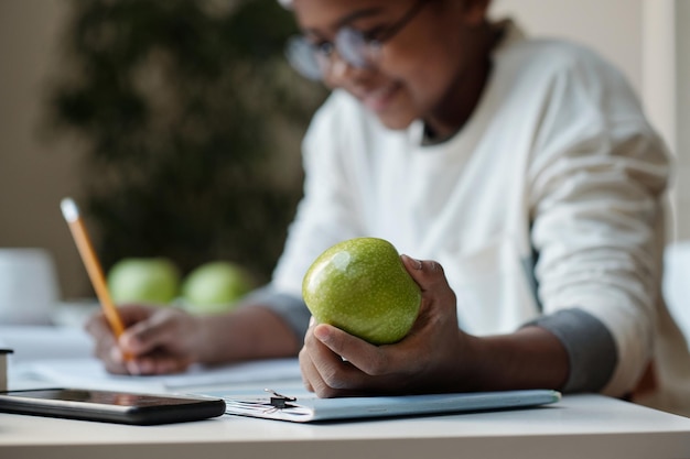 Céntrese en la mano del colegial que sostiene la manzana verde fresca