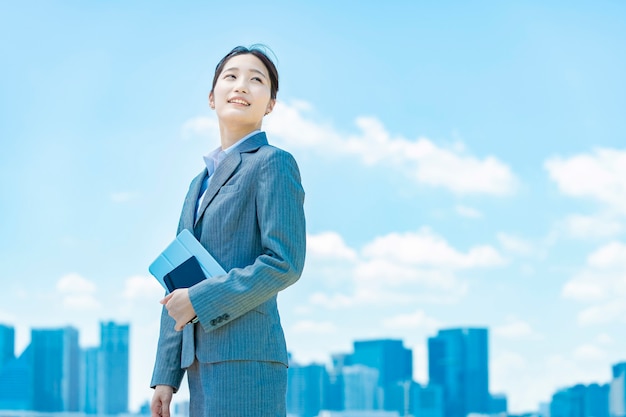 Centro de la ciudad, cielo azul y mujer de negocios joven asiática