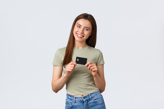 Centro comercial, estilo de vida e conceito de moda. Sorrindo feliz e atraente mulher em traje casual, mostrando cartão de crédito satisfeito, pronta para comprar novos produtos, indo se divertir nas lojas