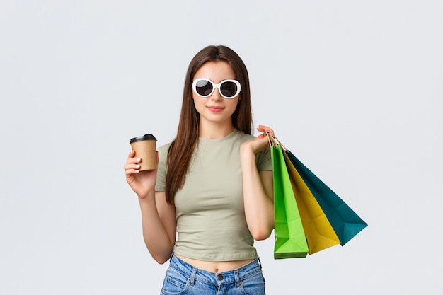 Centro comercial estilo de vida turismo y moda concepto elegante mujer despreocupada en gafas de sol bebiendo co ...