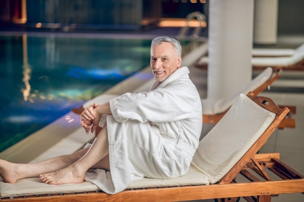 Centro de spa. um homem barbudo de cabelos grisalhos em um roupão de banho branco no centro de spa