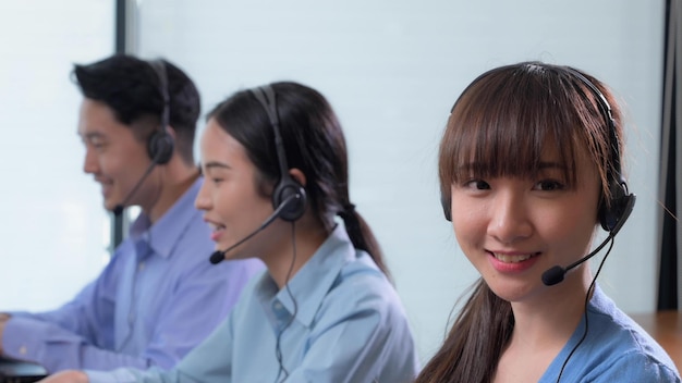 Centro de llamadas asiático y servicio al cliente usando una computadora portátil y usando auriculares