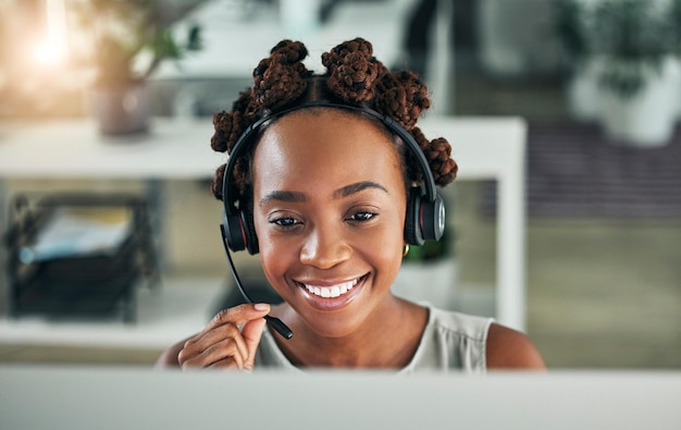 Centro de llamadas de cara y una mujer feliz con un micrófono en la computadora para servicio al cliente o ventas Sonrisa de una persona negra en una PC con auriculares como soporte de telemarketing crm o consultor de mesa de ayuda