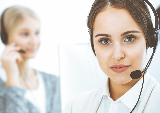 Foto centro de llamadas grupo de diversos operadores en el trabajo hermosa mujer en auriculares comunicándose