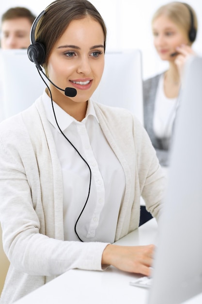 Centro de llamadas Grupo de operadores en el trabajo Centrarse en recepcionista hermosa mujer en auriculares