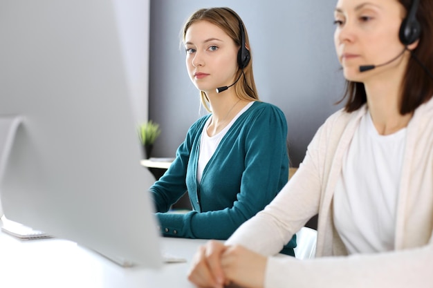 Centro de llamadas Grupo de operadores en el trabajo Centrarse en recepcionista hermosa mujer en auriculares