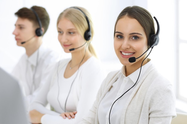 Centro de llamadas Grupo de operadores en el trabajo Centrarse en recepcionista hermosa mujer en auriculares