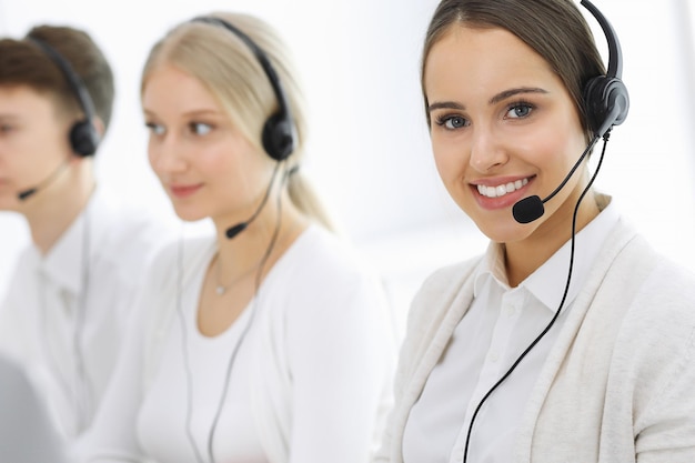 Centro de llamadas Grupo de operadores en el trabajo Centrarse en recepcionista mujer en auriculares en servicio al cliente