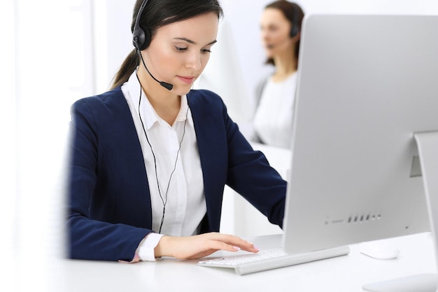 Centro de llamadas Hermosa mujer recepcionista sentada en auriculares en la oficina de servicio al cliente