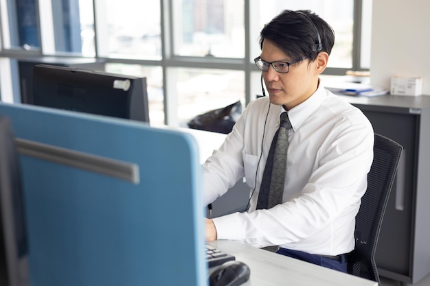 Centro de llamadas de servicio al cliente Atractivo hombre de negocios asiático y auriculares que trabajan con computadora en agentes de servicio al cliente de telemarketing