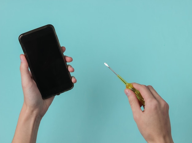 Centro de servicio Reparación de teléfonos inteligentes Mano femenina sostiene un destornillador y un teléfono inteligente