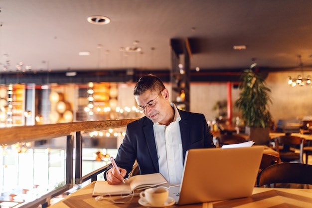 CEO escribiendo en agenda horario en café.