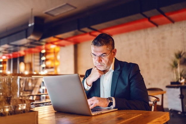 CEO usando laptop mientras está sentado en la cafetería.