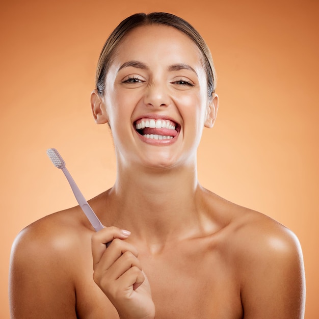 Cepillado de dientes mujer cuidado de la piel y retrato dental bienestar salud y limpieza cosméticos sobre fondo de estudio naranja Modelo joven feliz cara divertida lengua boca y pasta de dientes cepillo de dientes y sonrisa