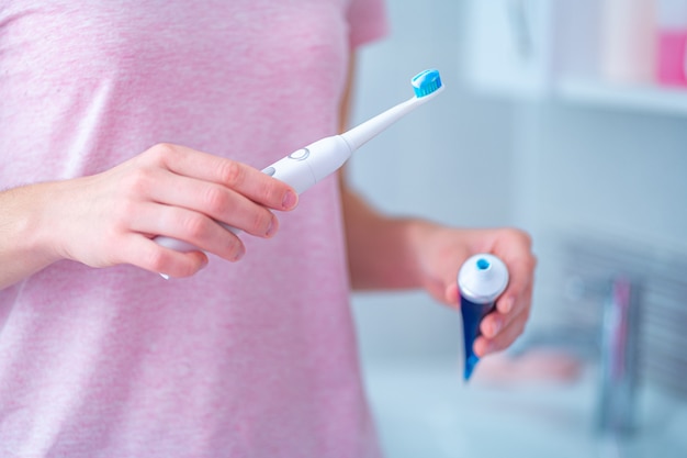 Cepillarse los dientes con un cepillo de dientes eléctrico ultrasónico y pasta de dientes en el baño de su casa