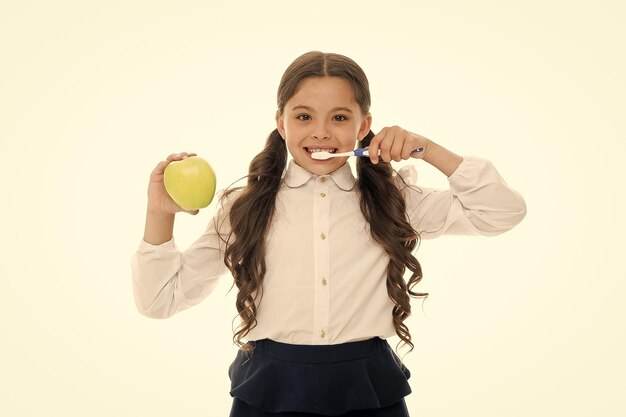 Cepillarse los dientes todos los días Concepto de higiene bucal Niña sostenga cepillo de dientes y fondo blanco de manzana Niño niña sostenga fruta y cepillo de dientes con pasta Niño colegiala niño feliz cuidado higiene bucal