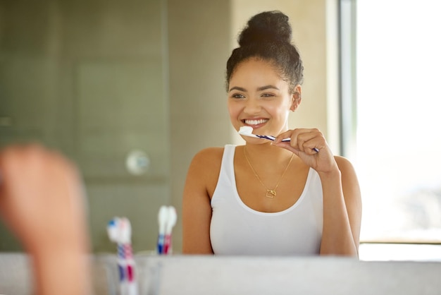 Foto cepíllelo dos veces al día para obtener una hermosa sonrisa foto de una mujer joven feliz y atractiva cepillándose los dientes