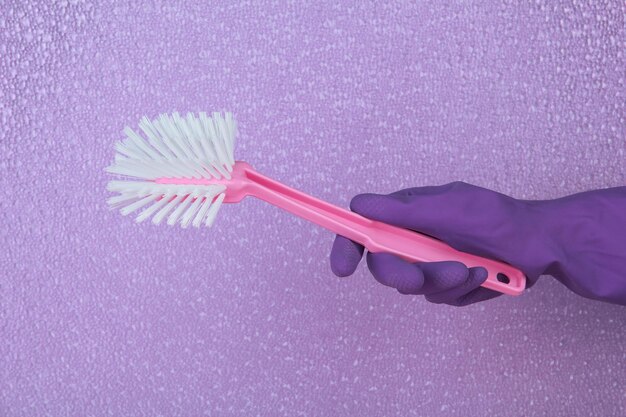 Cepillo de baño en mano sobre fondo púrpura