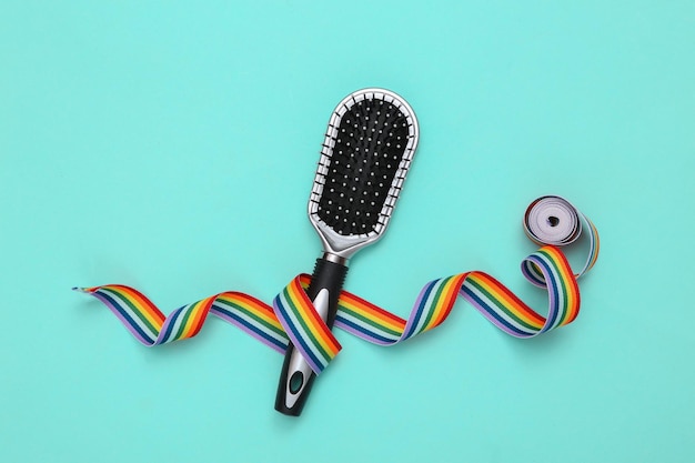 Cepillo para el cabello con cinta de arco iris sobre fondo azul Diseño de belleza