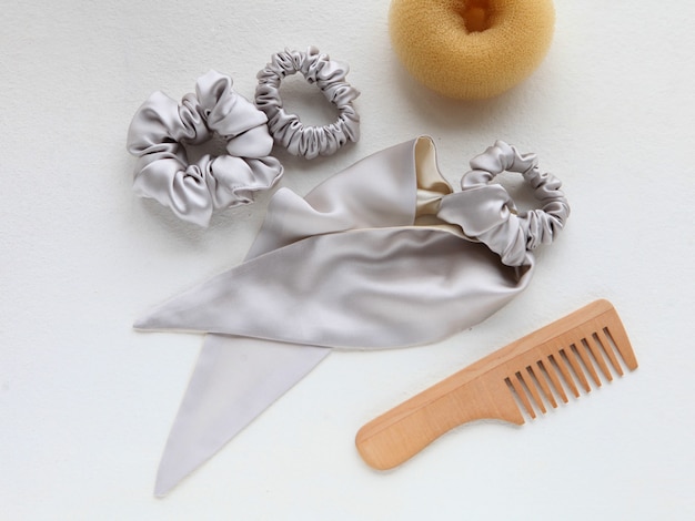 Cepillo para el cabello de madera y pasador de seda plateado sobre blanco accesorios de peluquería laicos planos