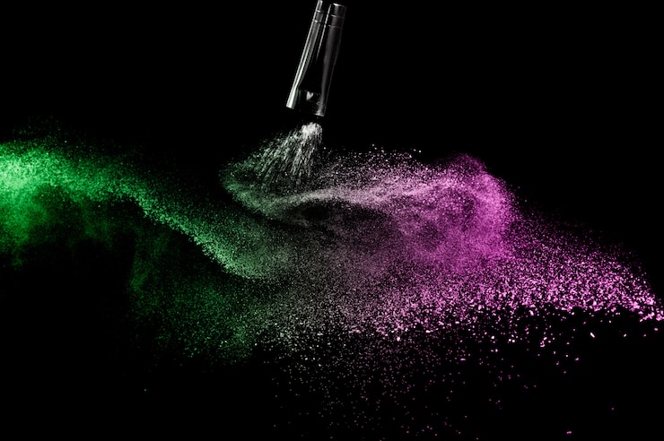 Foto cepillo cosmético con polvos cosméticos verdes y rosados que se extienden para maquillador y diseño gráfico en fondo negro