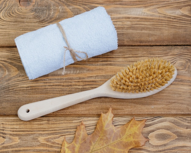 Cepillo de cuerpo de madera toalla azul y hoja de otoño sobre un fondo de madera Lugar para texto