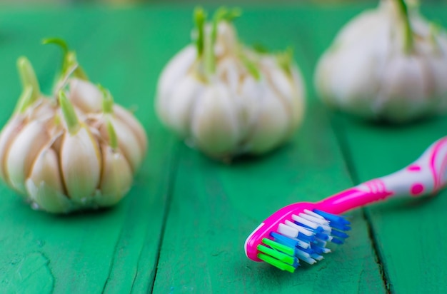 Cepillo de dientes y ajo sobre un fondo verde de madera