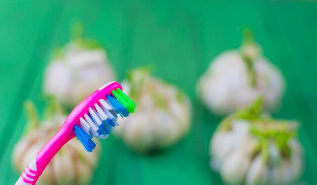 Cepillo de dientes y ajo sobre un fondo verde de madera