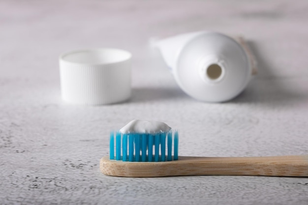 Cepillo de dientes de bambú con cerdas azules con pasta de dientes y un tubo de pasta de dientes en el fondo Enfoque selectivo